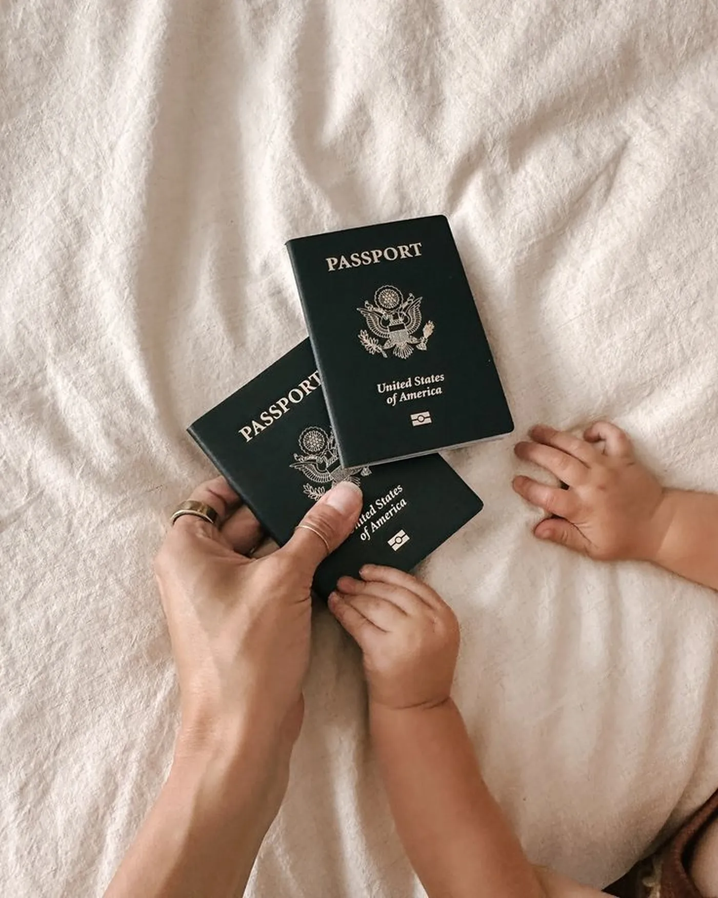 Mani di mamma e bambino con i passaporti sul letto, prima di partire in vacanza