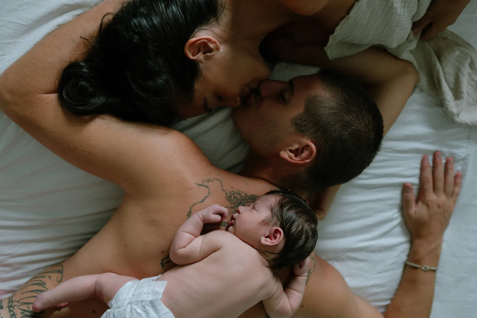 A mum and dad with their sleeping newborn, a tender moment