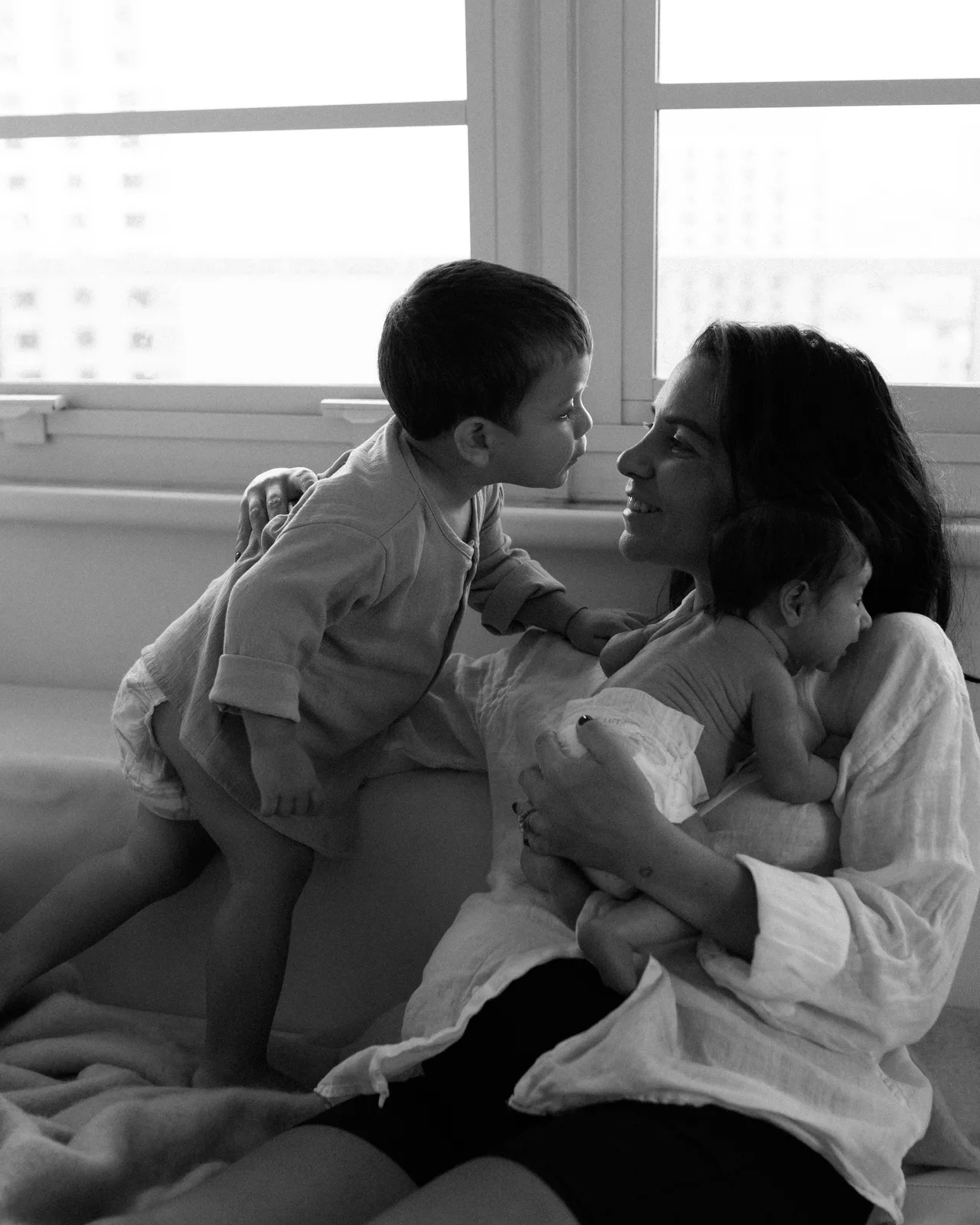Una mamma sul divano con i suoi due bambini