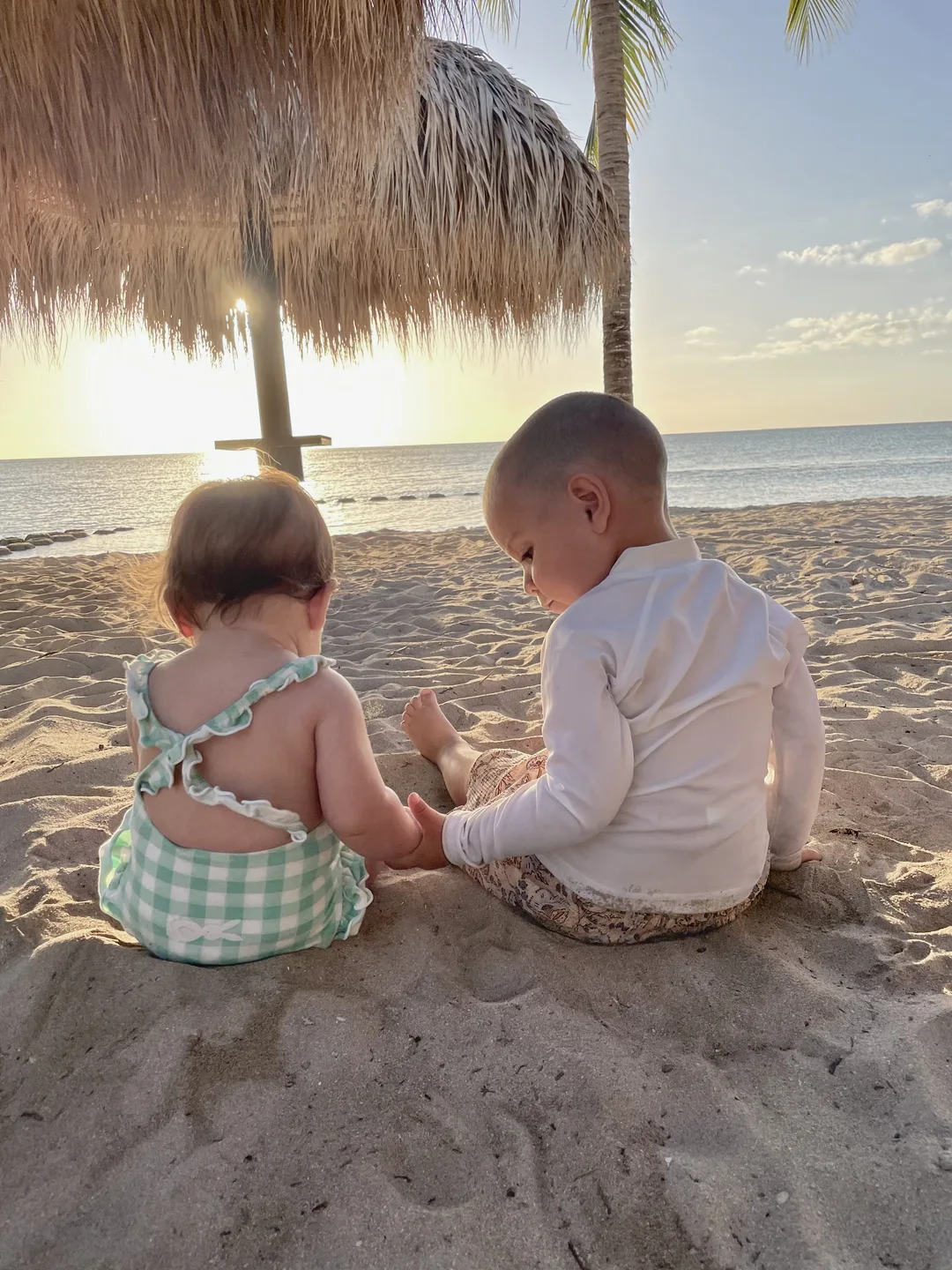 I due bimbi seduti sulla sabbia al tramonto, mano nella mano