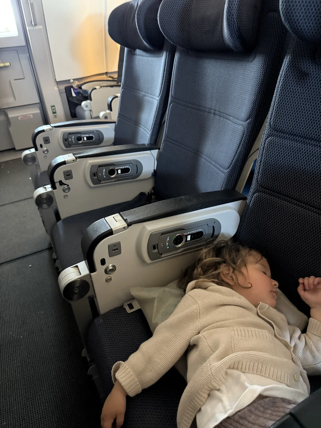 Bambina che dorme distesa sui sedili dell'aereo