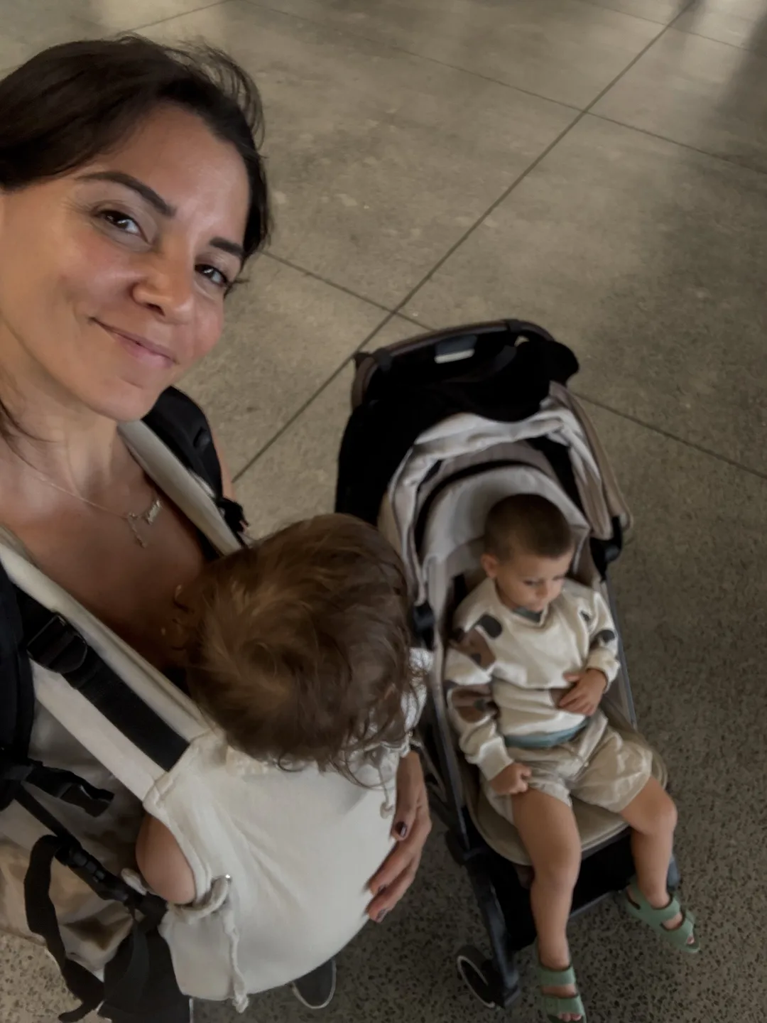 Federica in aeroporto con i due bimbi, uno nel marsupio e uno nel passeggino