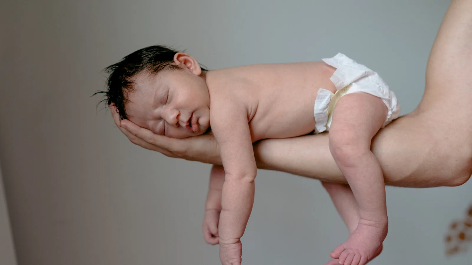 Neonato con le coliche confortato e tenuto in braccio dalla mamma